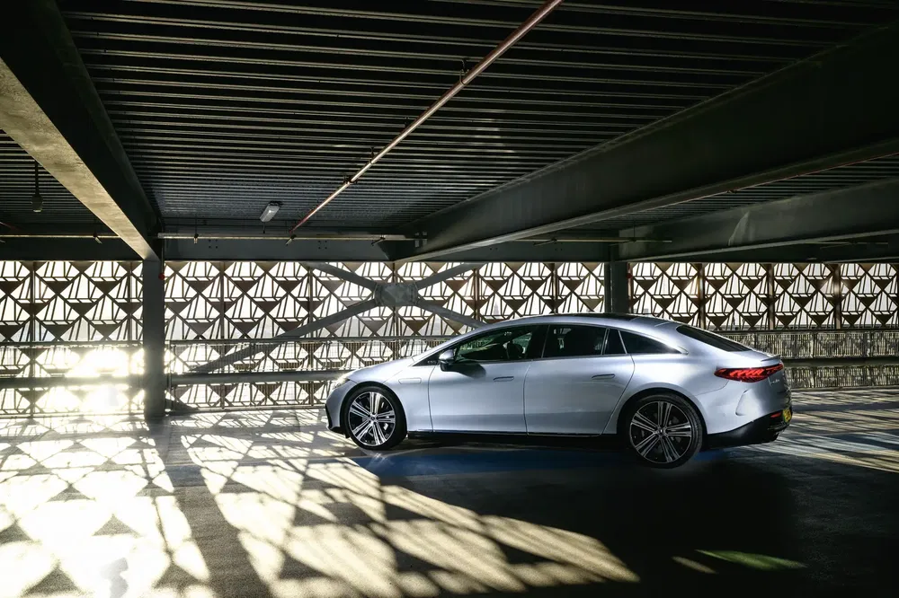 Mercedes-Benz EQS argent dans un parking sombre avec jeux d'ombres et lumière.