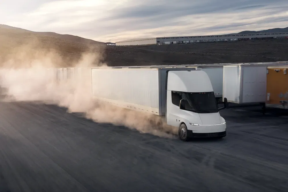 {"fr":"Camion Tesla Semi électrique roulant à grande vitesse, soulevant de la poussière sur une route. Paysage désertique en arrière-plan.","nl":"Elektrische Tesla Semi vrachtwagen rijdt snel, opwaaiend stof op een weg. Woestijnlandschap op de achtergrond."}