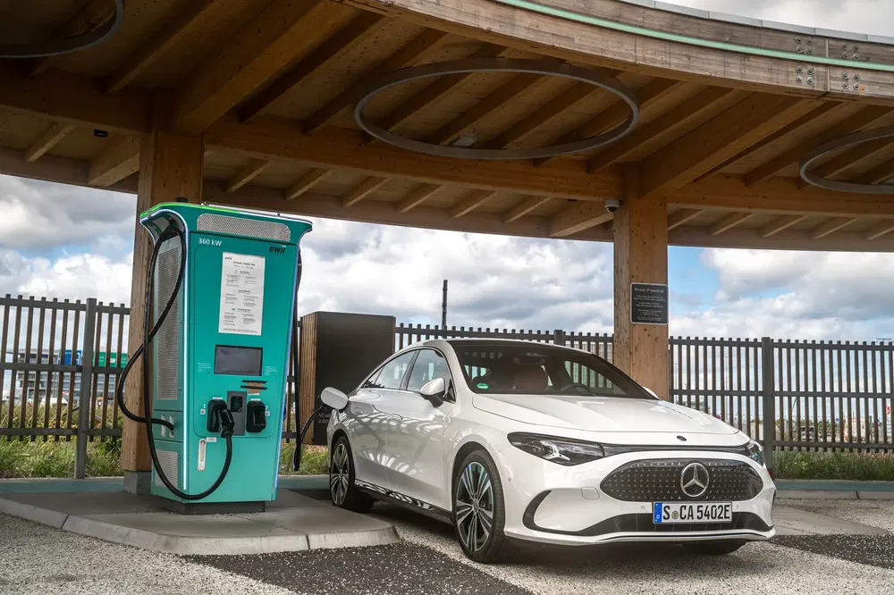 Witte elektrische Mercedes-Benz laadt op onder een moderne houten luifel.