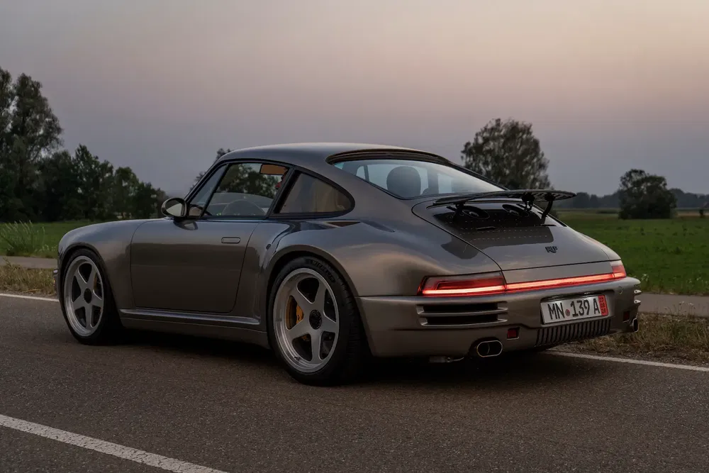 Klassieke Porsche op plattelandsweg bij schemering, unieke verlichte achterkant.