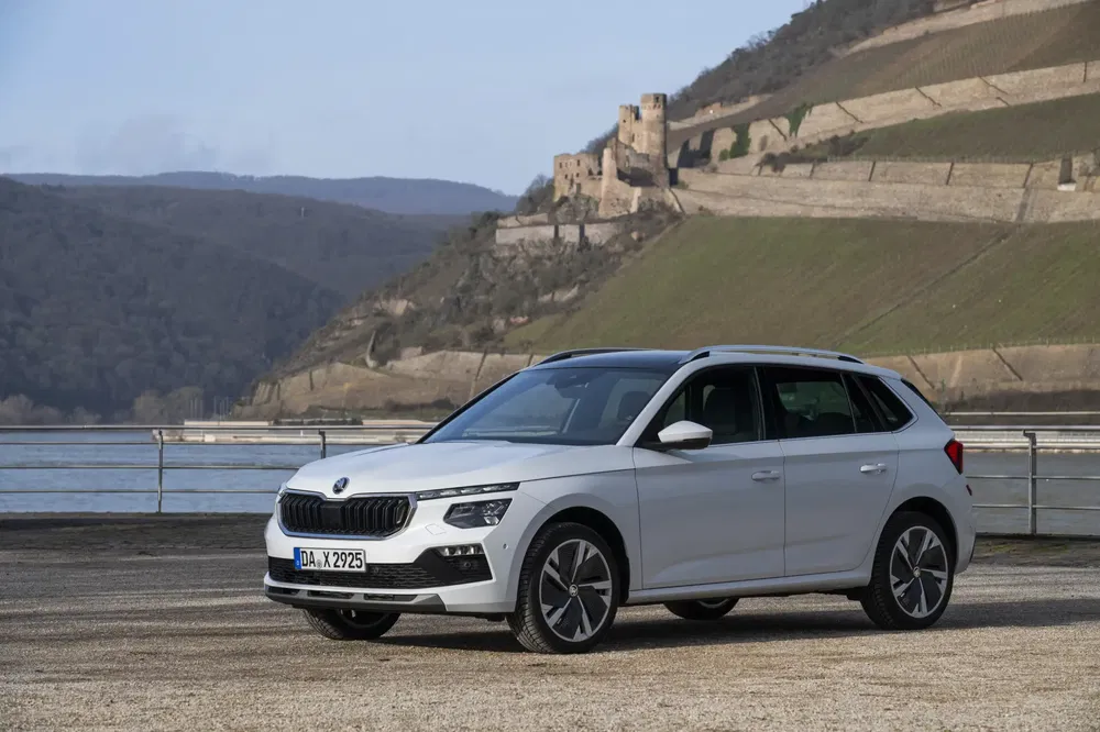 Škoda Kamiq witte SUV voor middeleeuws kasteel, heuvelachtig landschap.