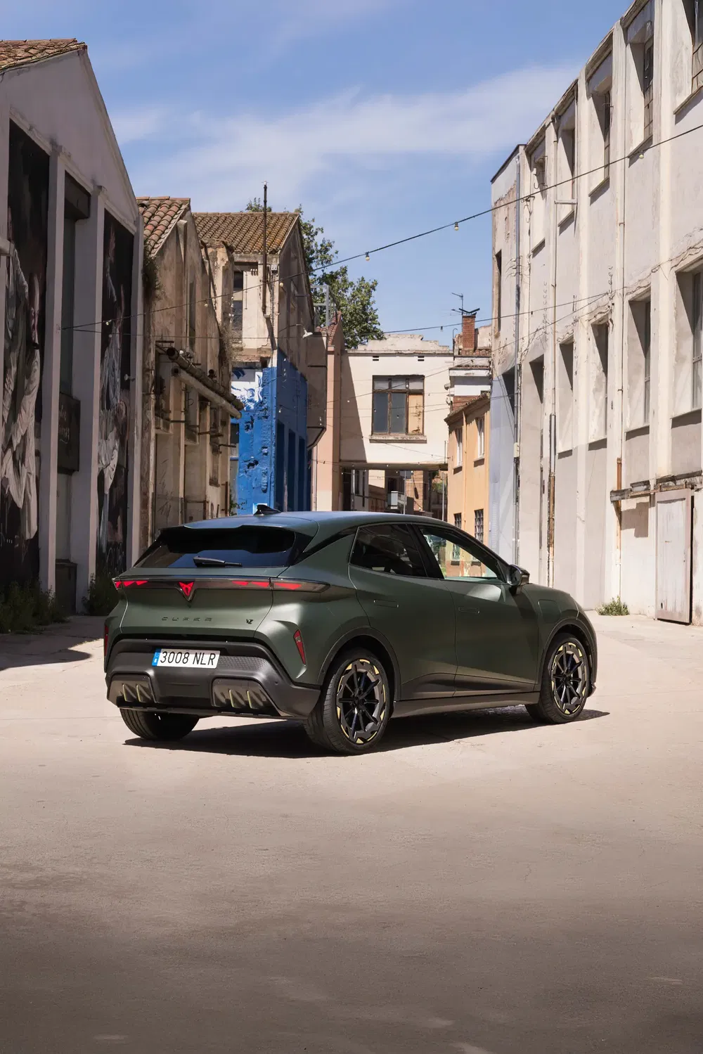 Cupra Tavascan vert dans une ruelle urbaine avec bâtiments anciens et graffitis.