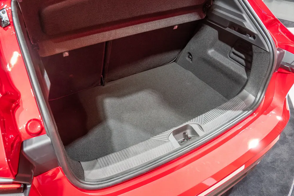Ruime kofferbak van een rode Toyota Corolla, met vilten interieur en neerklapbare achterstoelen.