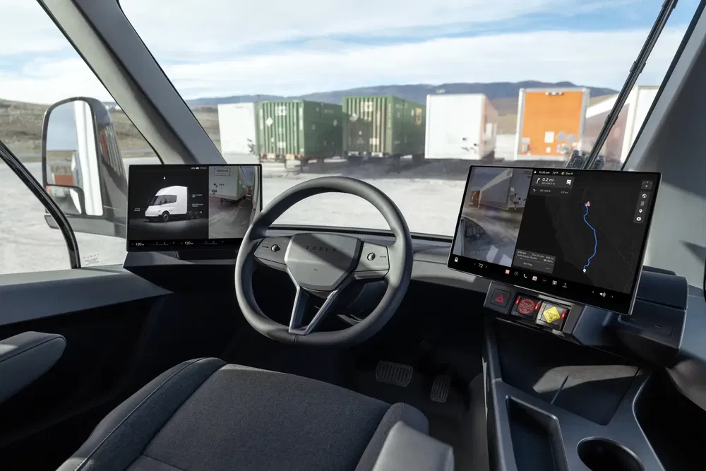 Intérieur d'un Tesla Semi avec tableaux de bord numériques, volant central et écrans de navigation.