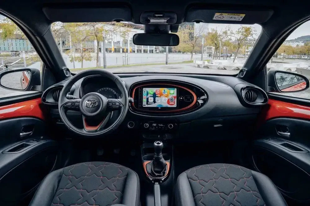 Intérieur de la Toyota Aygo X avec écran tactile et détails rouge vif.
