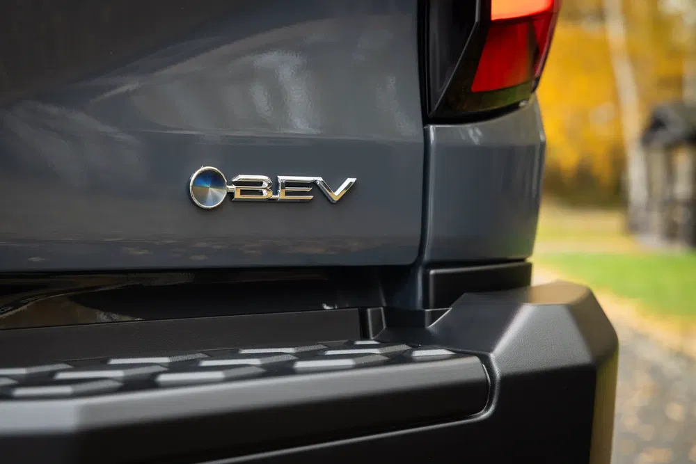 Gros plan du badge BMW iX5 BEV sur la carrosserie gris métallisé.