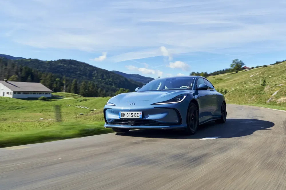 Voiture sportive électrique sur route de montagne, cadre naturel verdoyant.