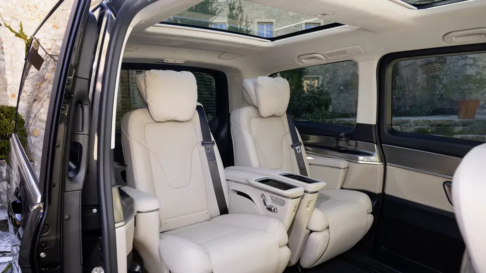 Luxe interieur van de Kia Carnival 2023 met witte lederen stoelen en panoramadak.