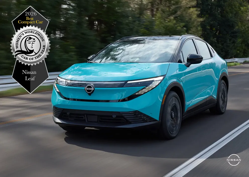 {"fr":"Nissan Leaf 2026 électrique, lauréat du prix, roulant sur une route bordée d'arbres.","nl":"Elektrische Nissan Leaf 2026, prijswinnaar, rijdend op een met bomen omzoomde weg."}