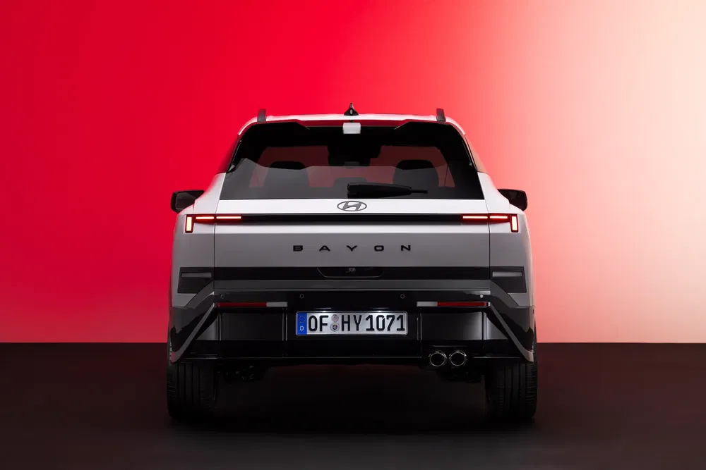 Vue arrière du Hyundai Bayon avec éclairage LED, fond rouge élégant.