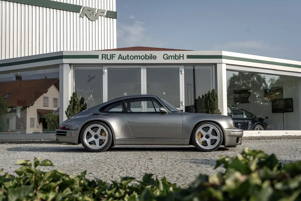 Zilveren RUF auto geparkeerd voor RUF Automobile GmbH showroom, sportief en stijlvol ontwerp.