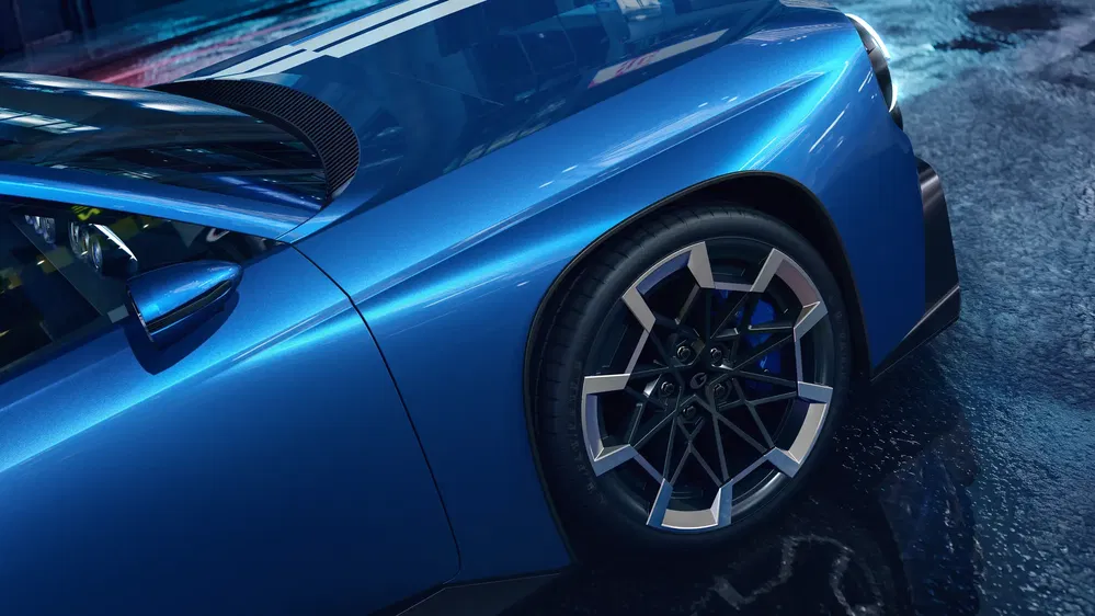 Vue latérale de la BMW i4 bleue avec roues sport modernes sur route mouillée.