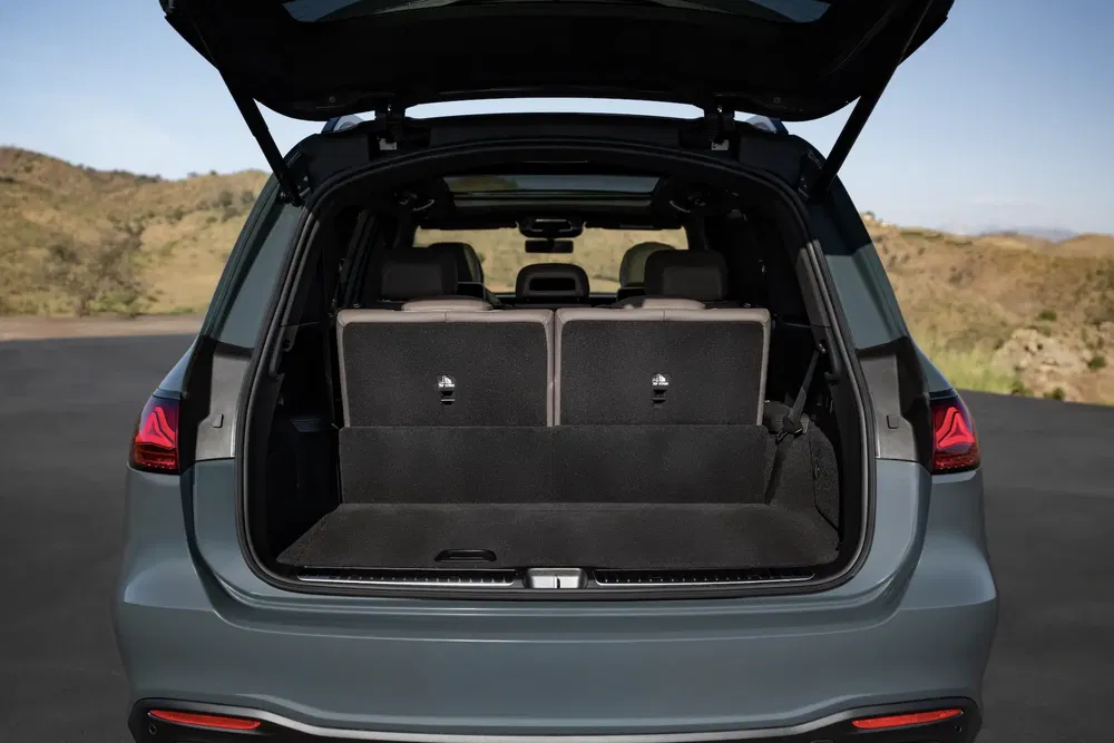 Coffre ouvert d'un SUV moderne avec sièges rabattables, paysage naturel en arrière-plan.