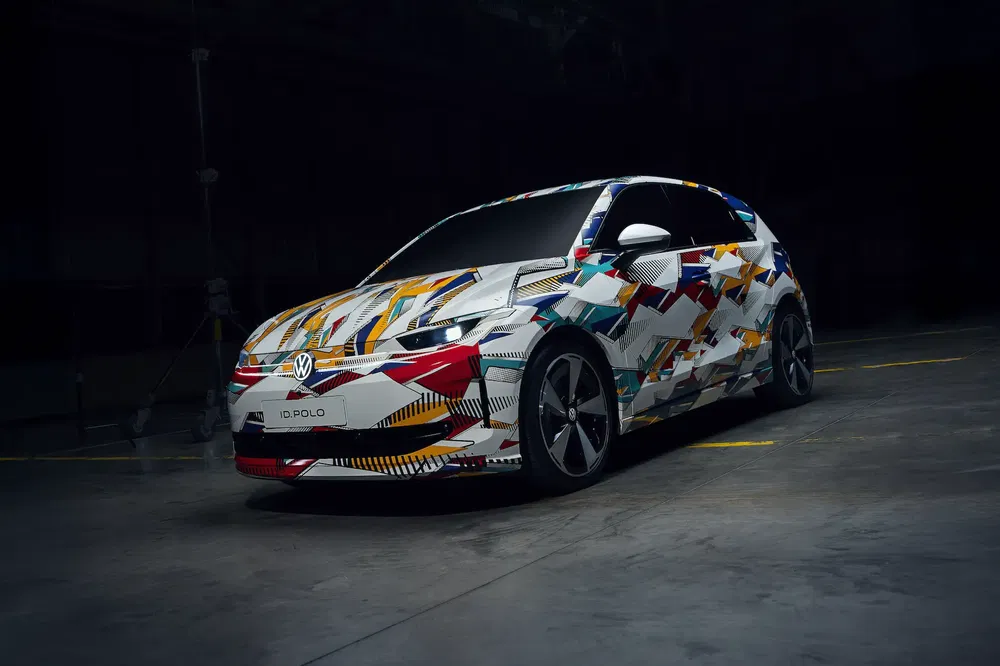 Volkswagen ID.Polo met kleurrijk grafisch ontwerp geparkeerd in een industriële omgeving.