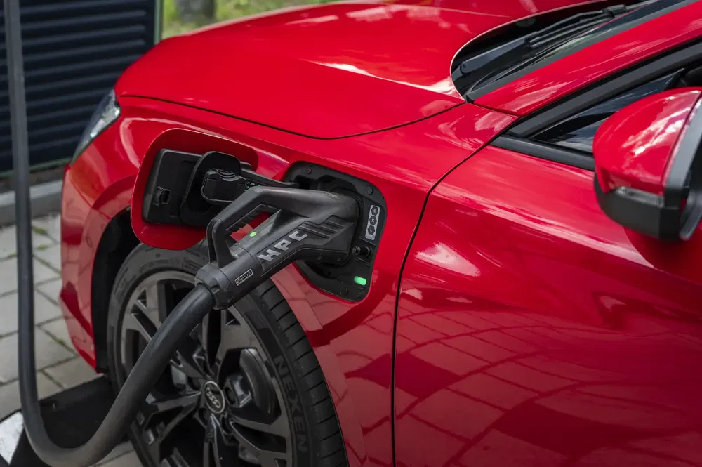 Voiture électrique rouge Audi en charge rapide HPC près de la roue avant.