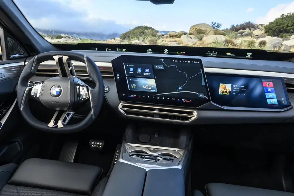 Moderne BMW-interieur met gebogen digitaal scherm, sportief stuur en panoramisch uitzicht.