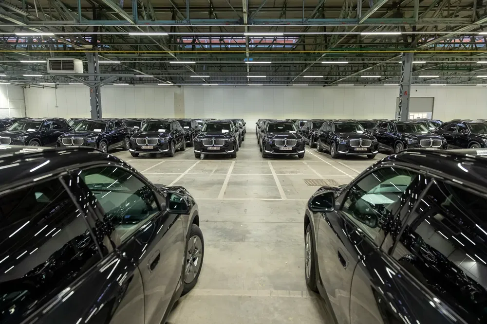 Stationnement de multiples véhicules électriques BMW dans un entrepôt spacieux bien éclairé.