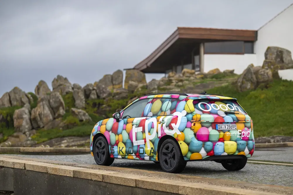 SUV Skoda Epiq in levendige kleuren geparkeerd voor een modern gebouw.