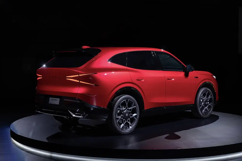 SUV Acura rouge sur un podium, éclairage subtil soulignant son design élégant et moderne.