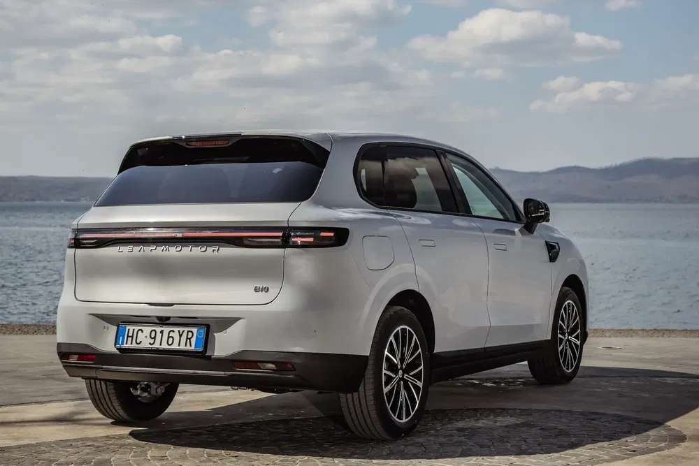 Witte Leapmotor SUV geparkeerd aan een meer met bewolkte lucht.