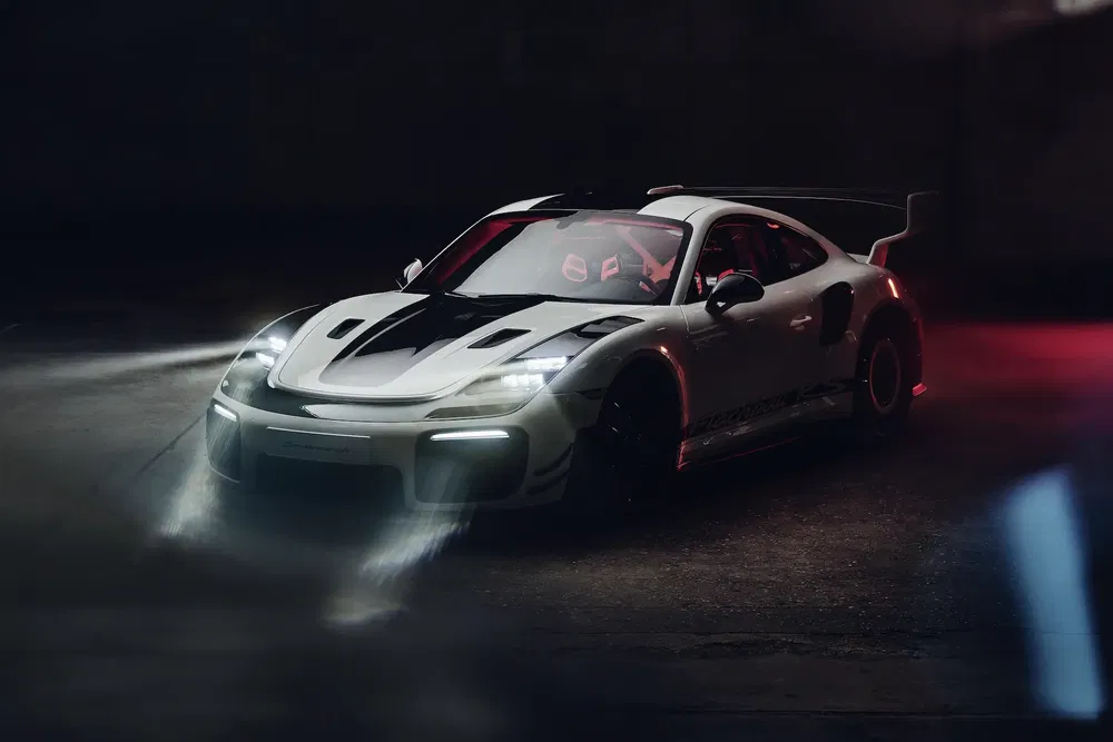Porsche 911 sportive avec phares allumés dans un garage sombre.