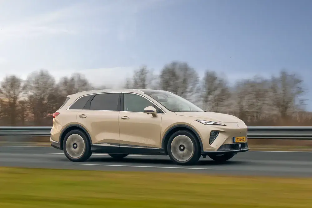 SUV électrique Nio ES6 beige roulant sur autoroute, arbres flous en arrière-plan.
