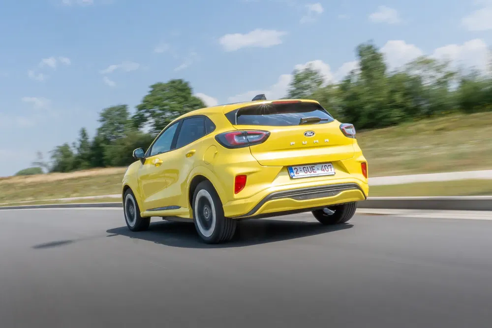 {"fr":"Ford Puma jaune sur route en plein air, montrant son design arrière moderne.","nl":"Gele Ford Puma rijdt op een weg met een moderne achterzijde ontwerp."}