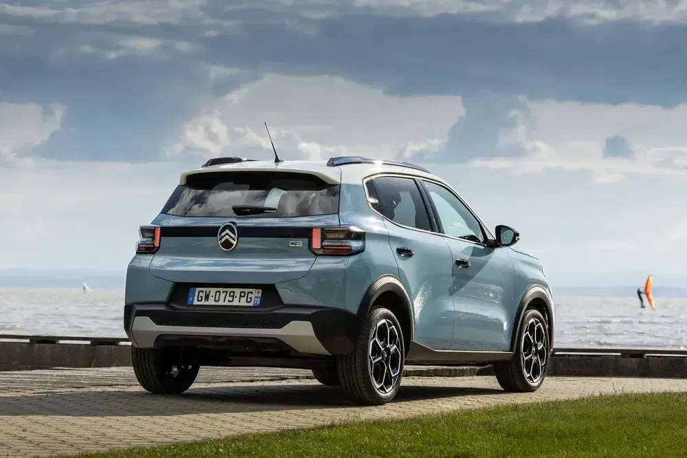 Blauwe Citroën C3 SUV geparkeerd bij een strand onder een bewolkte hemel.