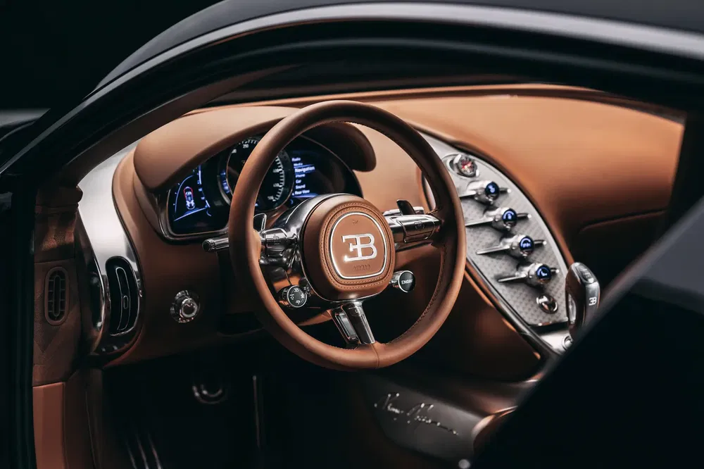 Intérieur de luxe Bugatti avec volant en cuir brun, tableau de bord high-tech.