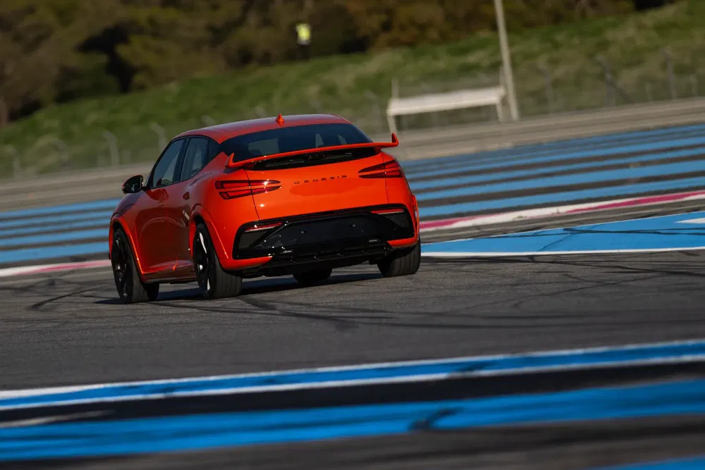 Maserati SUV orange vibrant en action sur piste de course sinueuse.