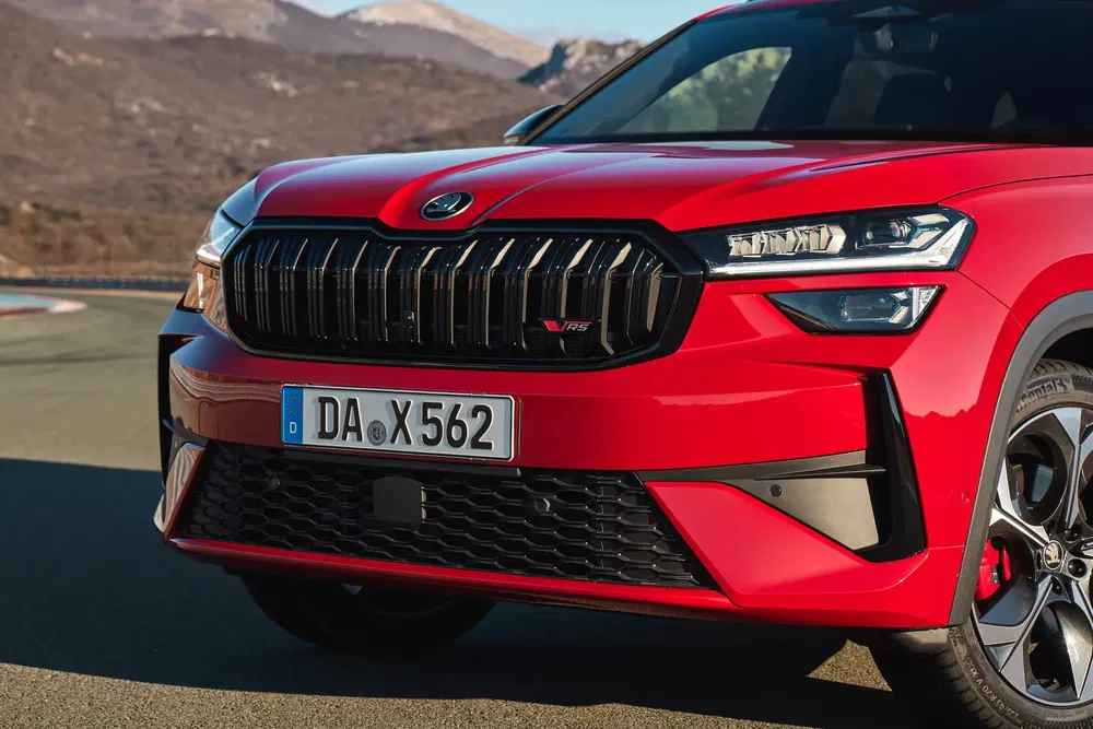 Gros plan Skoda Kamiq 2024 rouge, route de montagne, design avant distinctif.