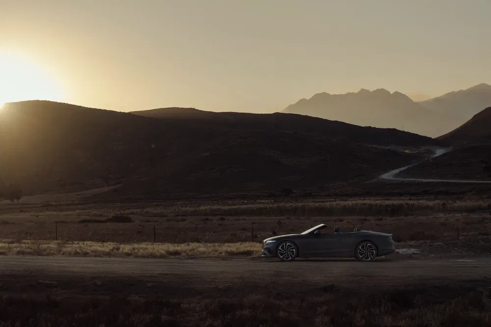 Voiture décapotable à l'arrêt sur route de campagne au coucher du soleil.