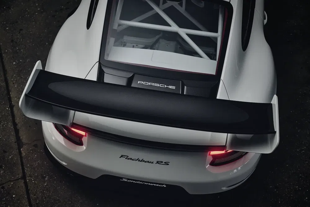 Vue arrière d'une Porsche Flachbau RS blanche avec aileron imposant et feu arrière.