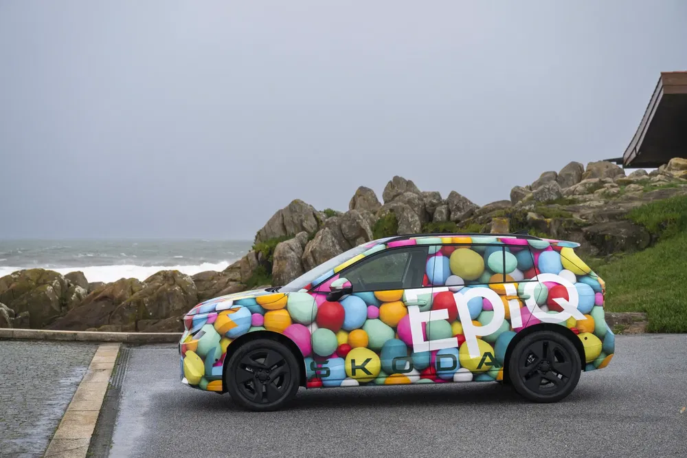 Kleurrijke Skoda SUV met ballonpatroon geparkeerd bij rotsen en de zee.