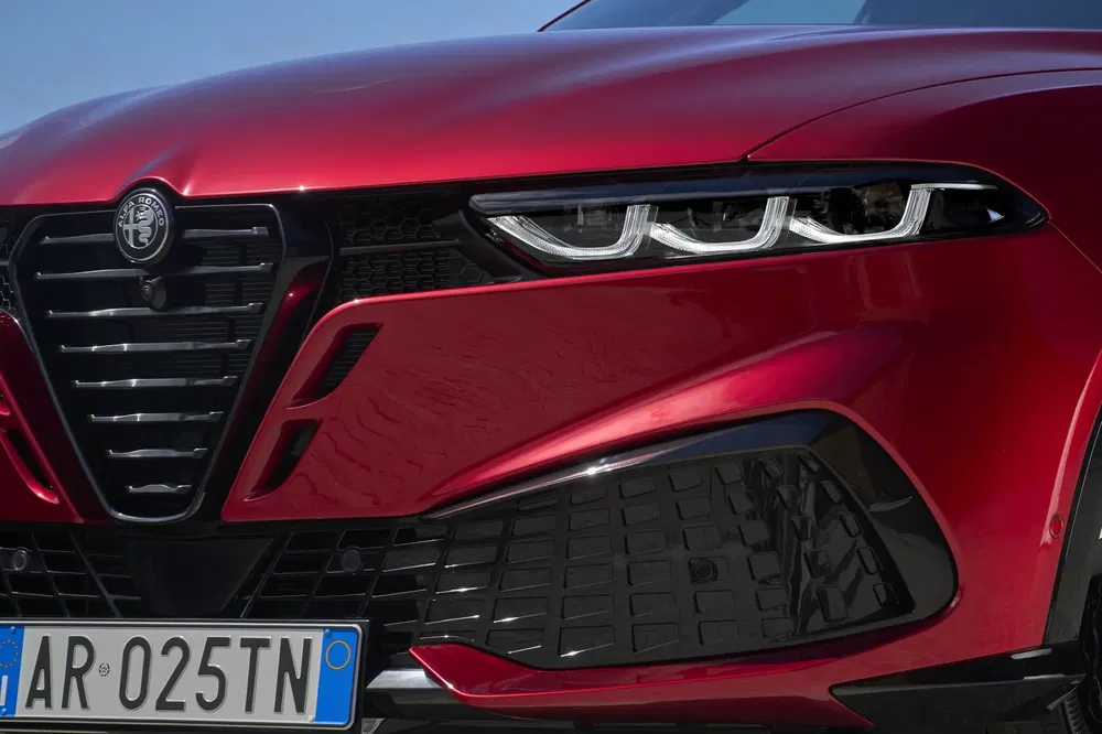 Close-up van grille en LED-koplampen van een glanzende rode Alfa Romeo.
