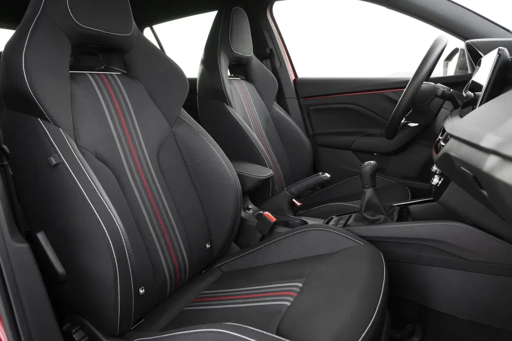Intérieur d'une voiture sportive avec sièges noirs à rayures rouges et grises.