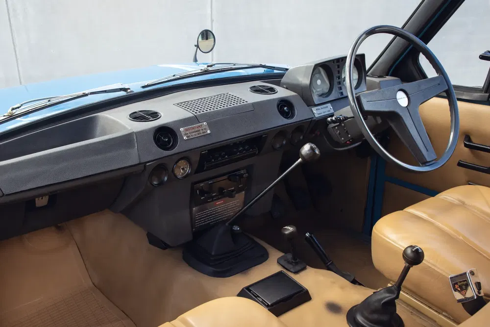 Intérieur vintage d'une voiture Alfa Romeo, volant à droite, tableau de bord classique beige.