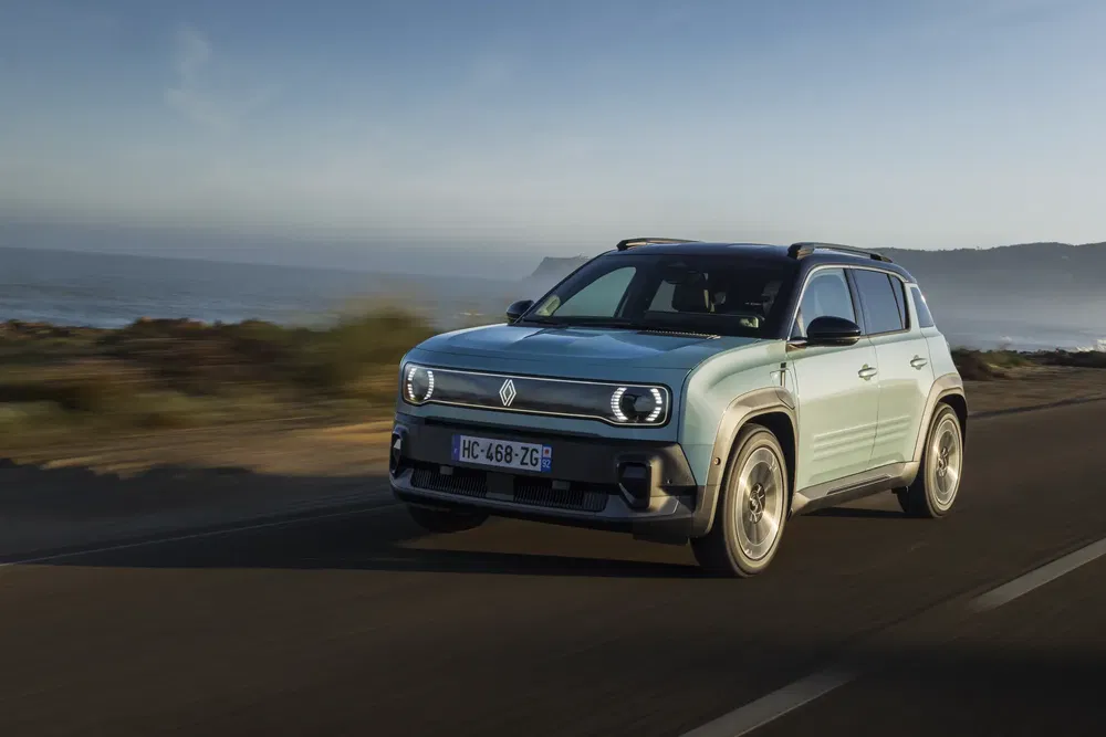 Renault 4EVER Trophy SUV roulant sur une route côtière au coucher du soleil.