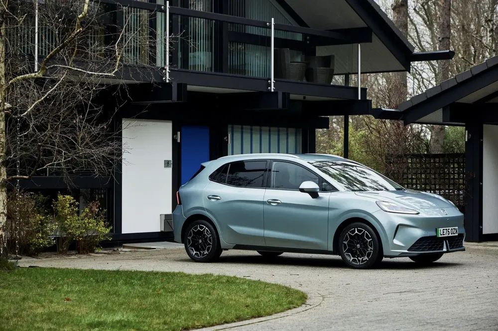 Elektrische MG4 geparkeerd voor een modern huis, met strak en elegant ontwerp.