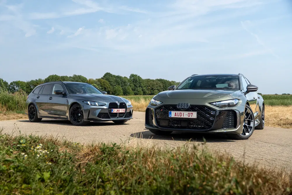 BMW M3 en Audi RS6 stationwagens op landweg met landelijke achtergrond.