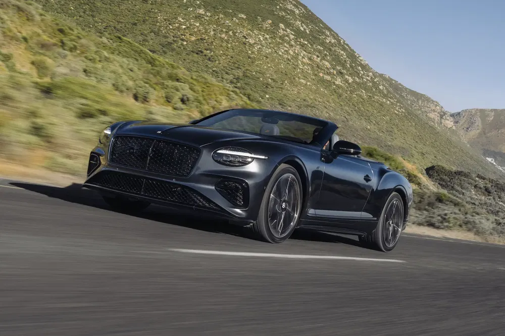 Bentley Continental GT Cabriolet sur route sinueuse en montagne panoramique.