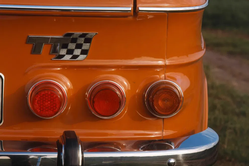 Details van achterlichten en TT-logo op een klassieke oranje auto.