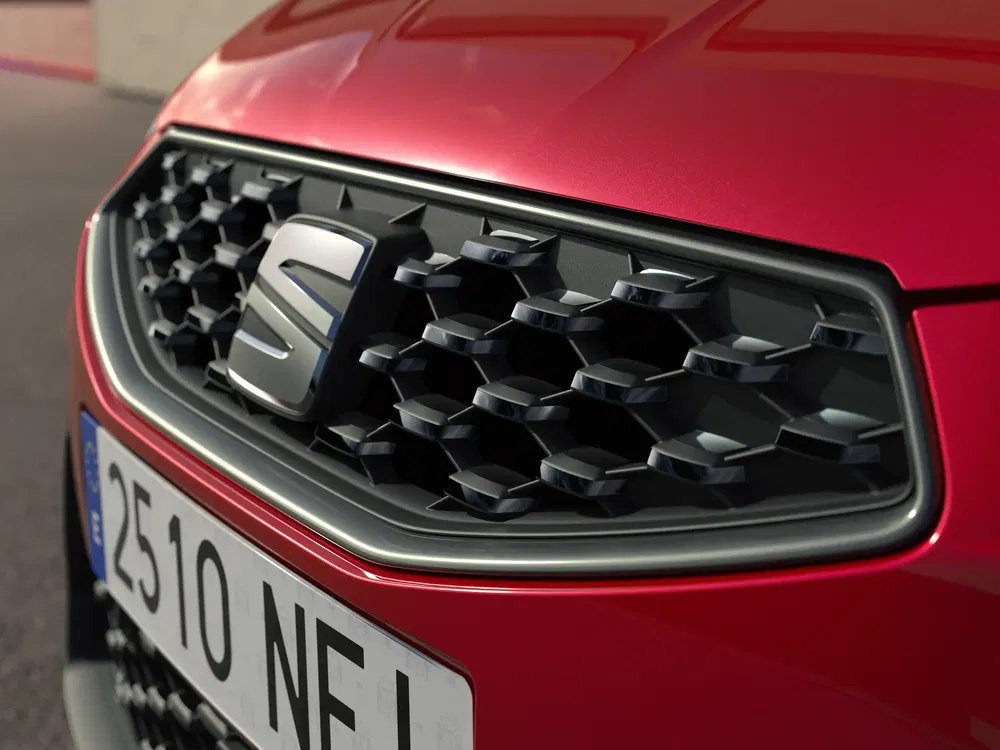 Close-up van Seat-grille met iconisch logo, glimmende rode auto.