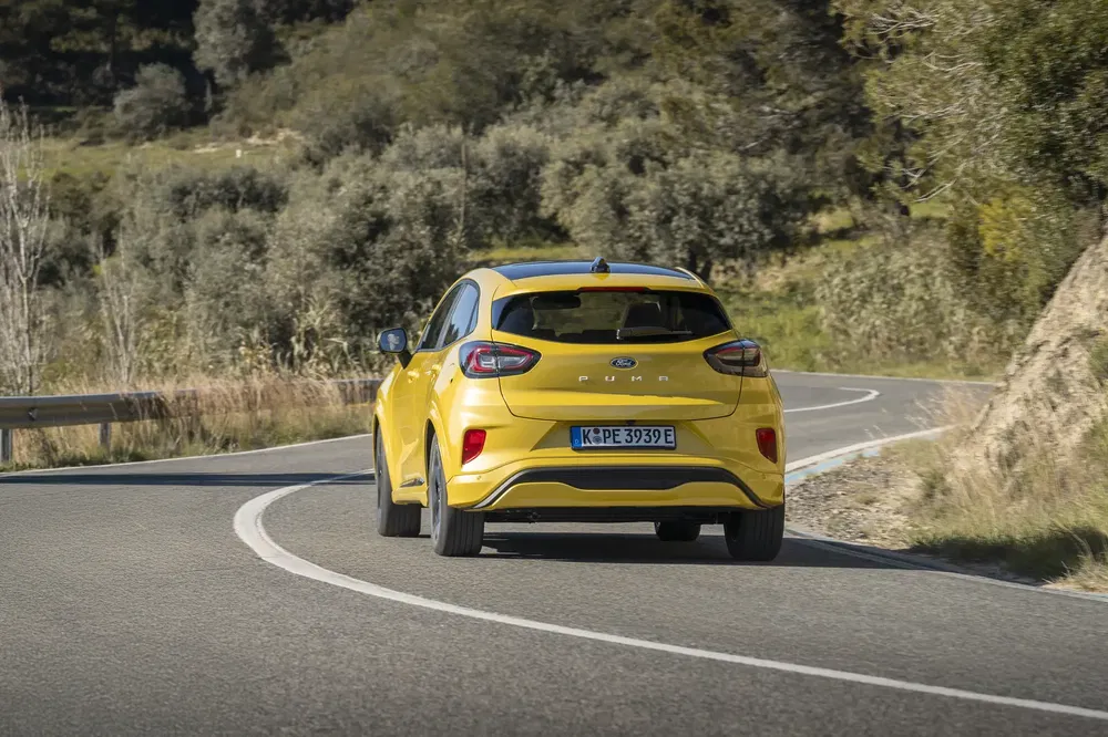 Ford Puma jaune sur route sinueuse entourée de verdure.