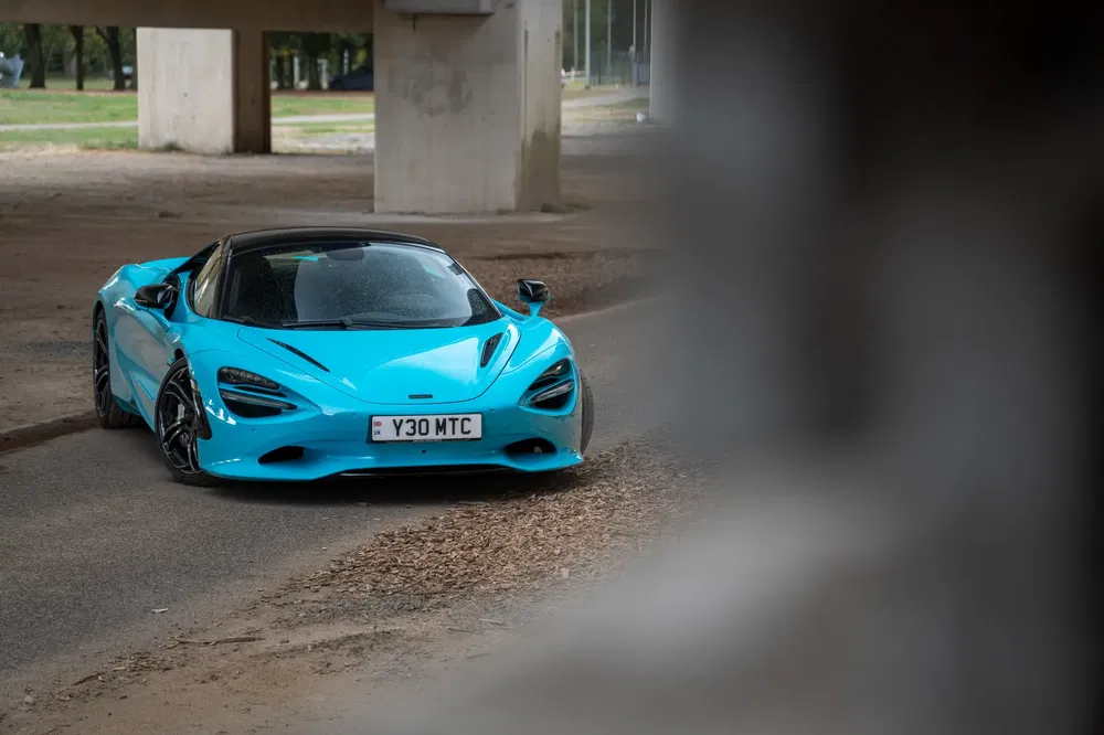 McLaren 720S bleu vif sous un pont, véhicule sportif de haute performance.
