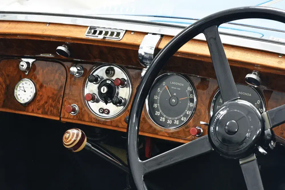 Tableau de bord en bois d'une voiture Lagonda classique avec volant noir et cadrans rétro.