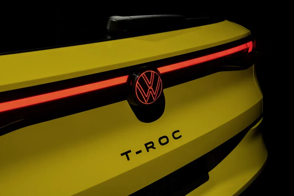 {"fr":"Arrière du Volkswagen T-Roc jaune avec logo éclairé et signature lumineuse distincte.","nl":"Achterkant van gele Volkswagen T-Roc met verlicht logo en opvallende lichtsignatuur."}