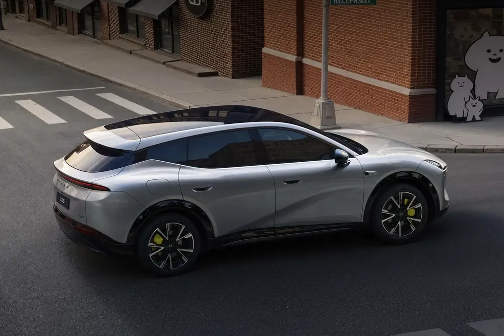 SUV électrique argenté sur route urbaine avec design futuriste et jantes sportives.