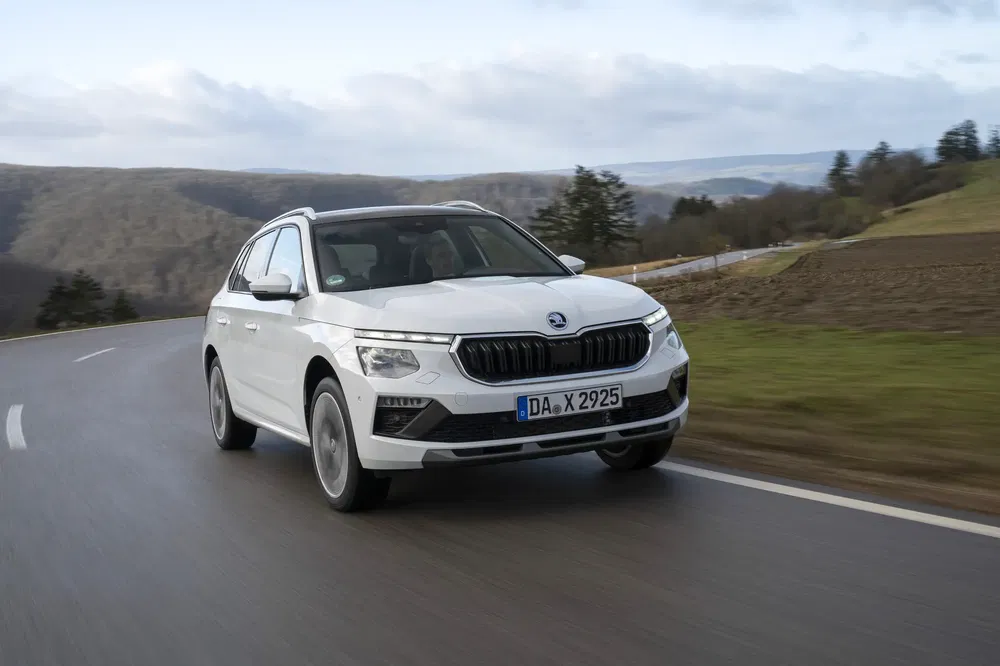 SUV blanc Skoda sur route de campagne sinueuse avec paysage vallonné.