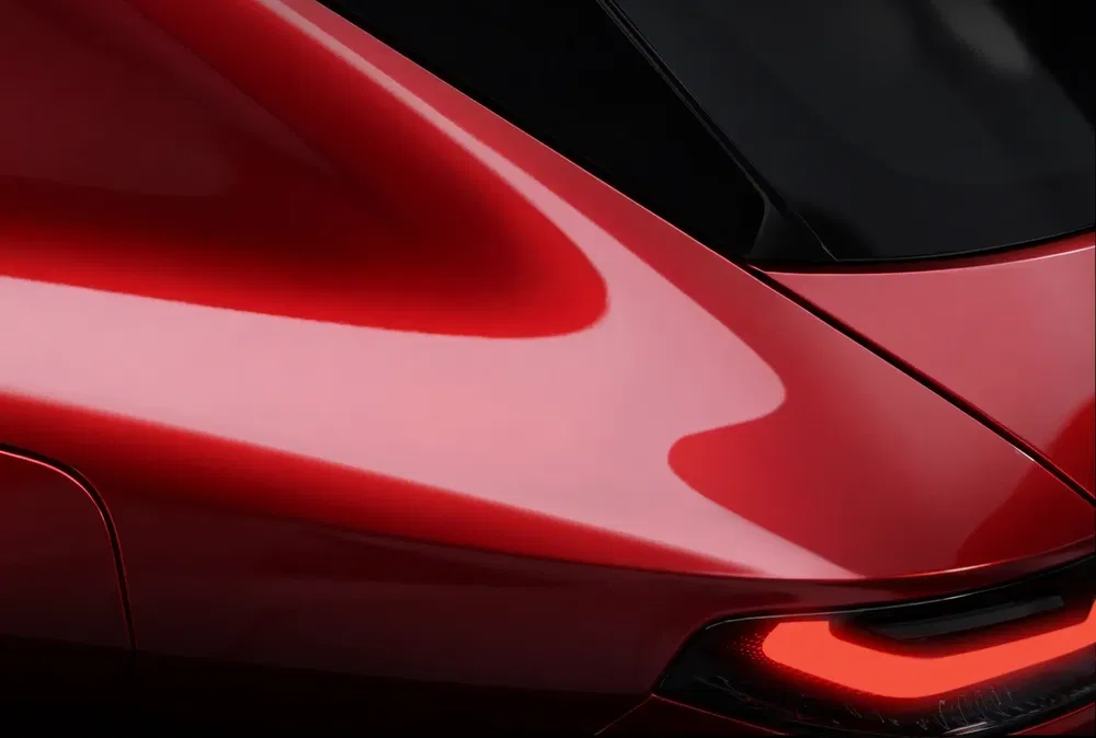 Détail d'une voiture rouge avec un design aérodynamique et un feu arrière moderne.